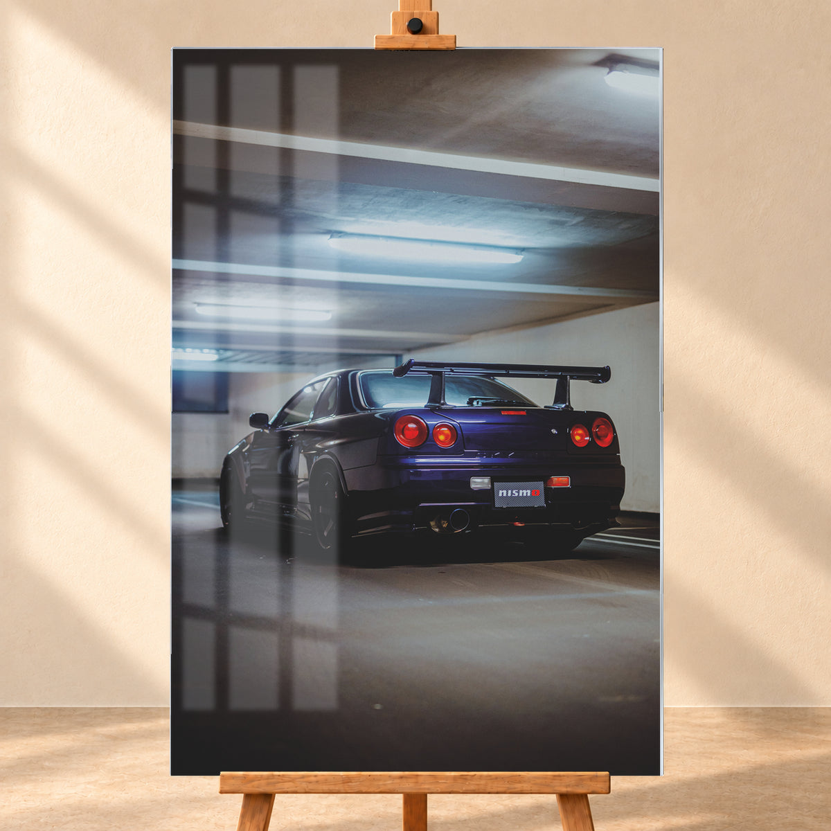 Dunkelvioletter Nissan Skyline R34 in tiefer Heckdreiviertelansicht in einem Parkhaus, mit vier runden roten Rückleuchten, großem Heckflügel, dunklen Rädern und kühlen Deckenleuchten; Visualisierung als Acrylglas-Wandbild, frontal auf einer Holzstaffelei.
