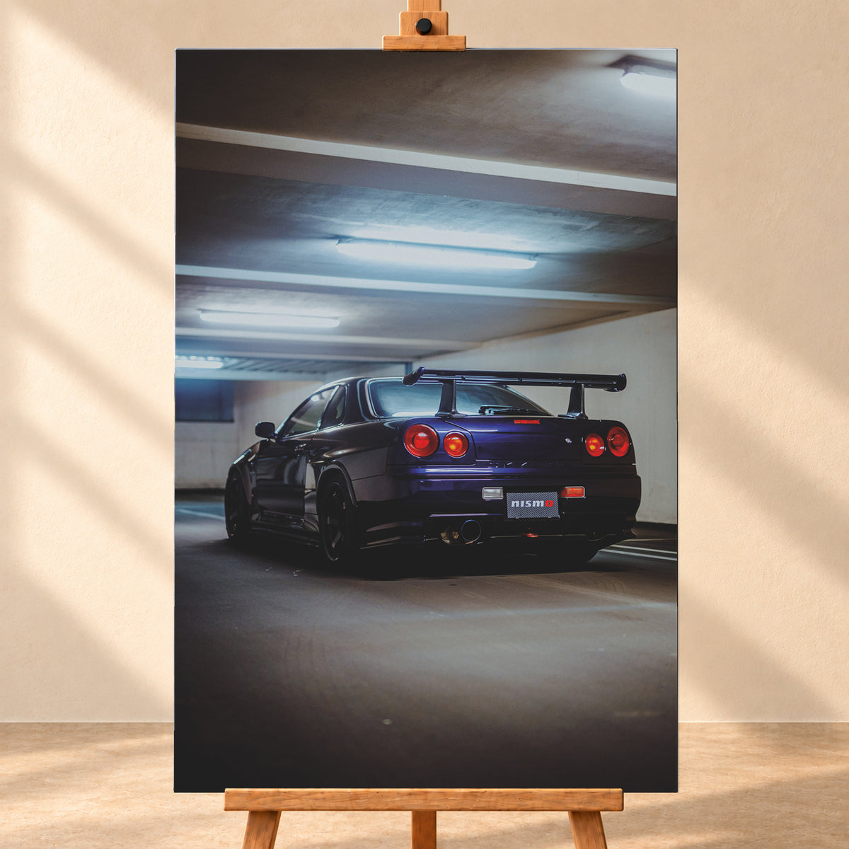 Dunkelvioletter Nissan Skyline R34 in tiefer Heckdreiviertelansicht in einem Parkhaus, mit vier runden roten Rückleuchten, großem Heckflügel, dunklen Rädern und kühlen Deckenleuchten; Visualisierung als Leinwand-Wandbild, frontal auf einer Holzstaffelei.