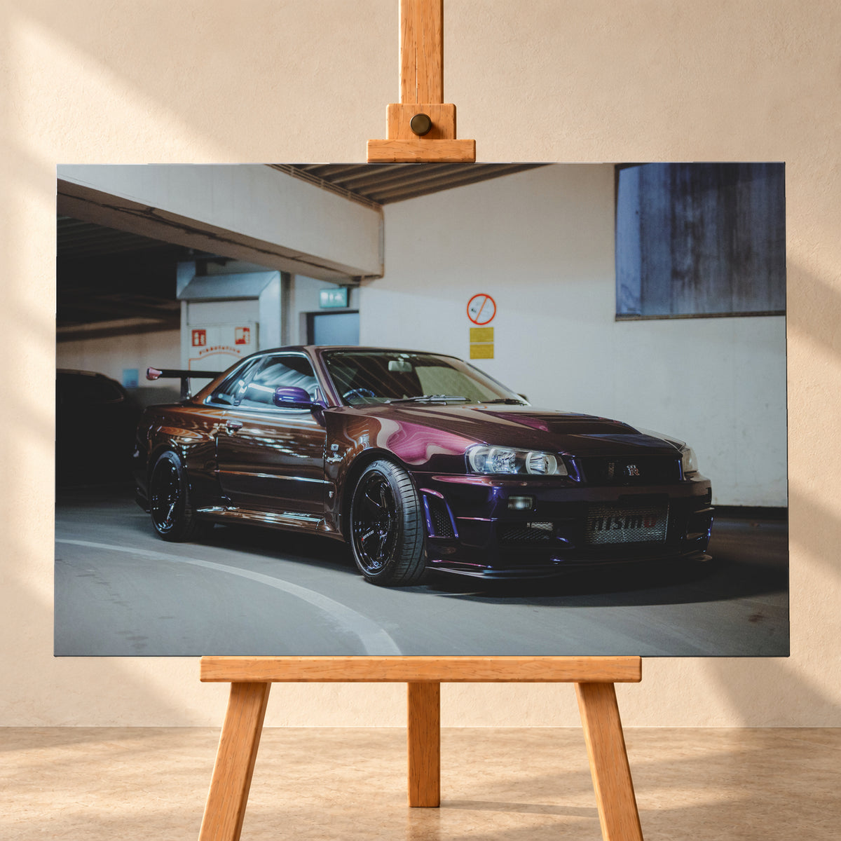 Dunkelvioletter Nissan Skyline R34 in einem Parkhaus, schräg von vorn fotografiert, mit schwarzen Rädern, großem Heckflügel und pink-violetten Lichtreflexionen auf der Karosserie; Visualisierung als Leinwand-Wandbild, frontal auf einer Holzstaffelei.
