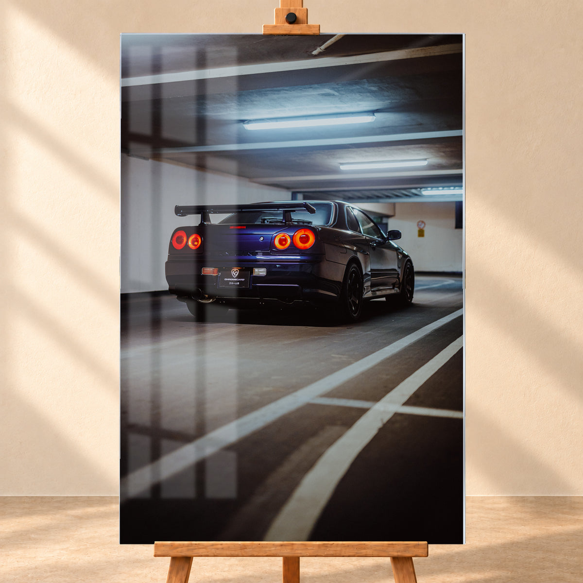 Dunkelblauer Nissan Skyline R34 in tiefer Dreiviertel-Heckansicht in einer Parkgarage; vier rote Rundrücklichter leuchten unter kühlen Deckenlampen, weiße Bodenlinien führen durch das Hochformat; Visualisierung als Acrylglas-Wandbild, frontal auf einer Holzstaffelei.