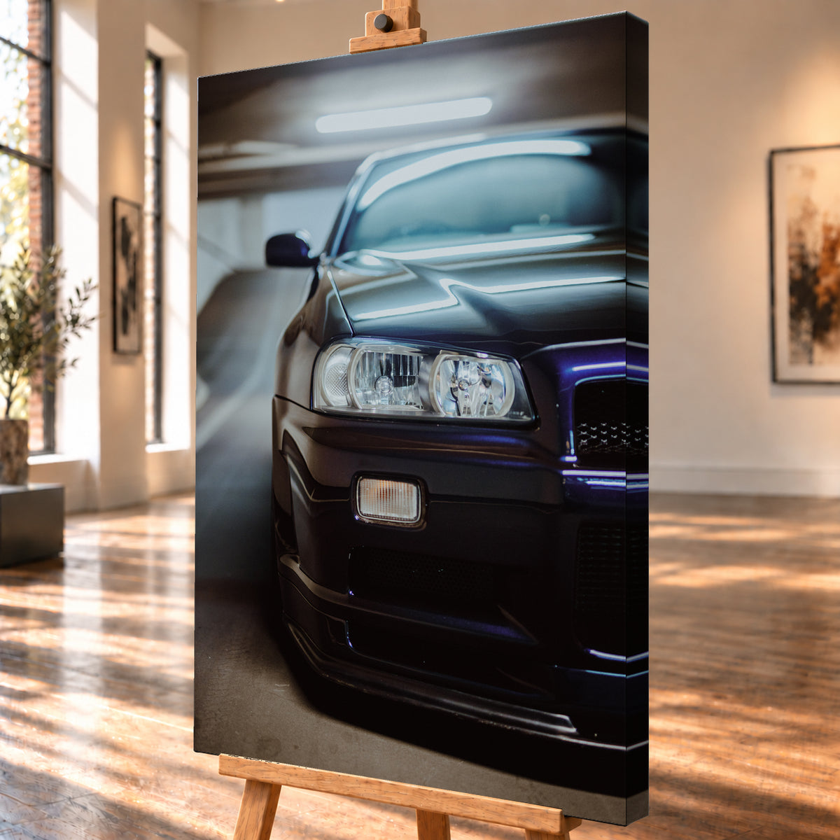 Dunkler Nissan Skyline in naher, leicht versetzter Frontansicht in einem Parkhaus. Sichtbar sind Scheinwerfer, Stoßfänger, Motorhaube, Windschutzscheibe und Seitenspiegel mit kühlen blau-violetten Lichtreflexen; Visualisierung als Leinwand-Wandbild, schräg von der Seite auf einer Holzstaffelei.