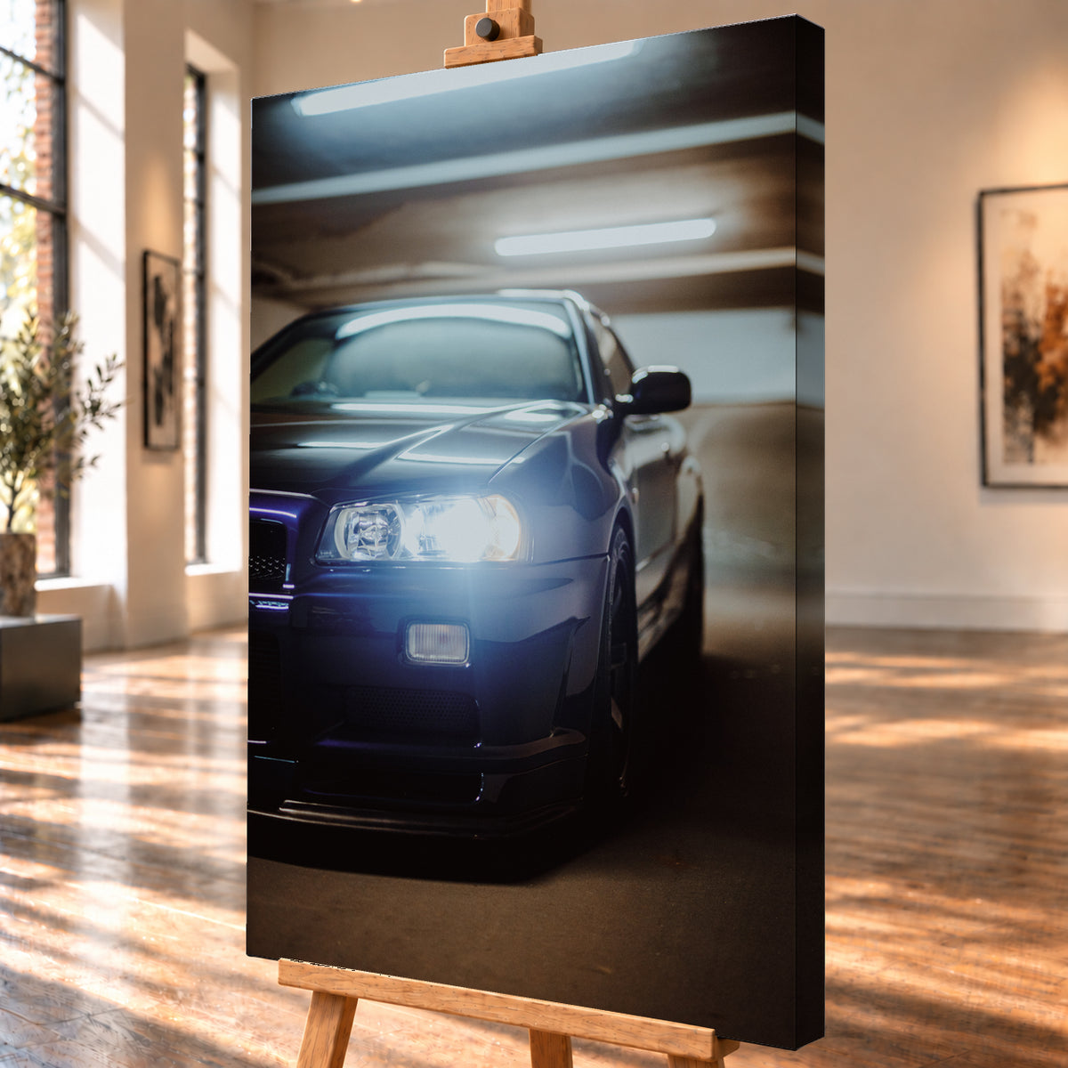 Hochformatige Nahaufnahme eines dunkelblau bis schwarz wirkenden Nissan Skyline R34 in schräger Frontansicht. Ein heller Frontscheinwerfer leuchtet in die Kamera, während sich kühle rechteckige Deckenlichter auf Motorhaube und Windschutzscheibe spiegeln. Das Fahrzeug steht in einem warm beleuchteten, unscharfen Innenraum; Visualisierung als Leinwand-Wandbild, schräg von der Seite auf einer Holzstaffelei.