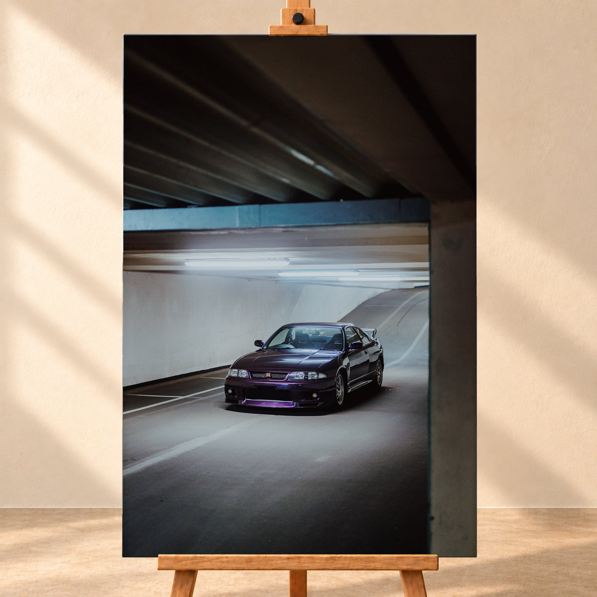 Dunkelvioletter Nissan Skyline in vorderer Dreiviertelansicht in einer Beton-Tiefgarage, beleuchtet von kühlen Deckenleuchten; Fahrbahnlinien und eine Rampe liegen im Hintergrund; Visualisierung als Leinwand-Wandbild, frontal auf einer Holzstaffelei.