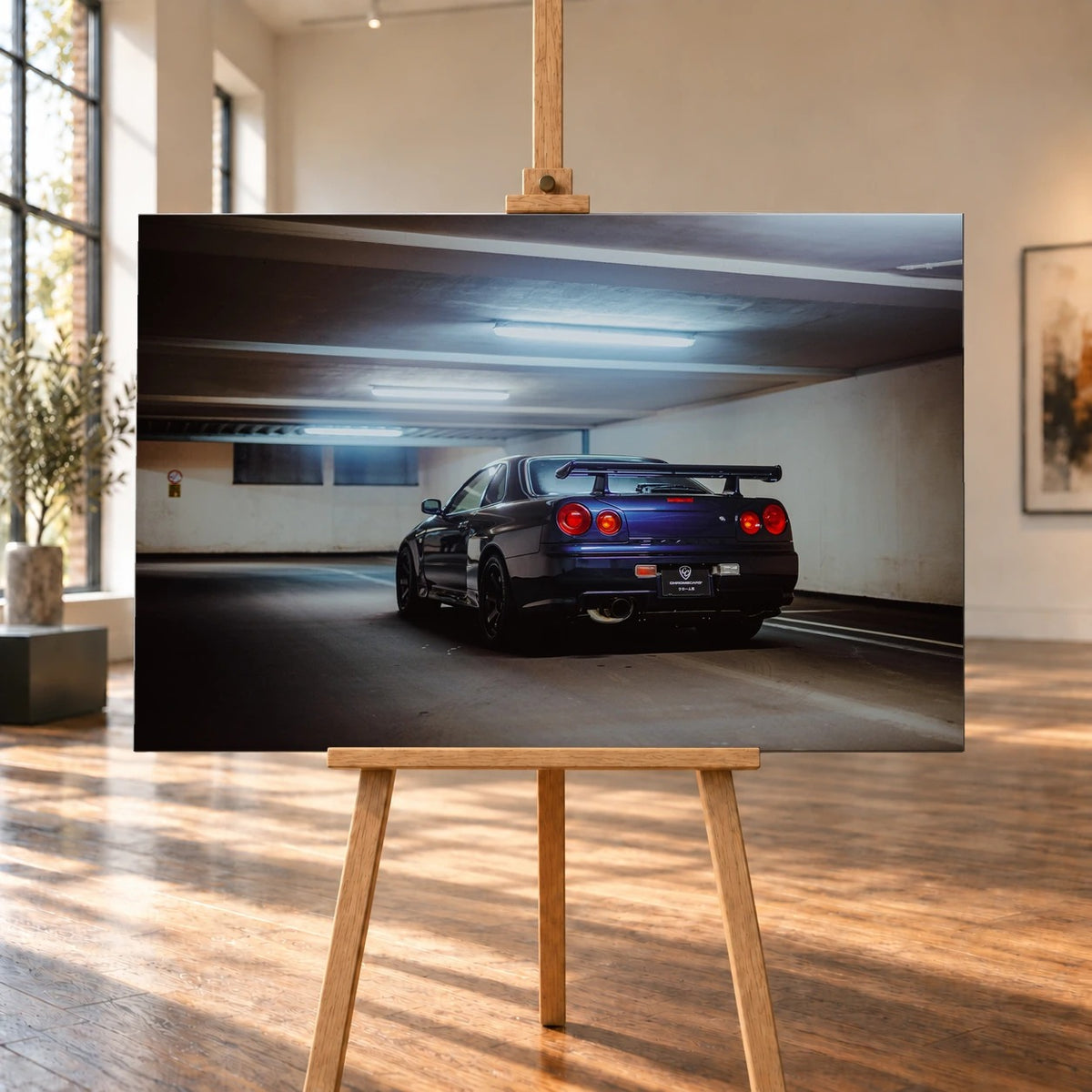 Visualisierte Raumansicht eines querformatigen Leinwandbilds auf einer Holzstaffelei in einem hellen Raum mit hohen Fenstern und Holzboden. Auf dem Bild steht ein dunkelvioletter Nissan Skyline R34 schräg von hinten in einer Tiefgarage; sein großer Heckflügel ist deutlich zu erkennen.