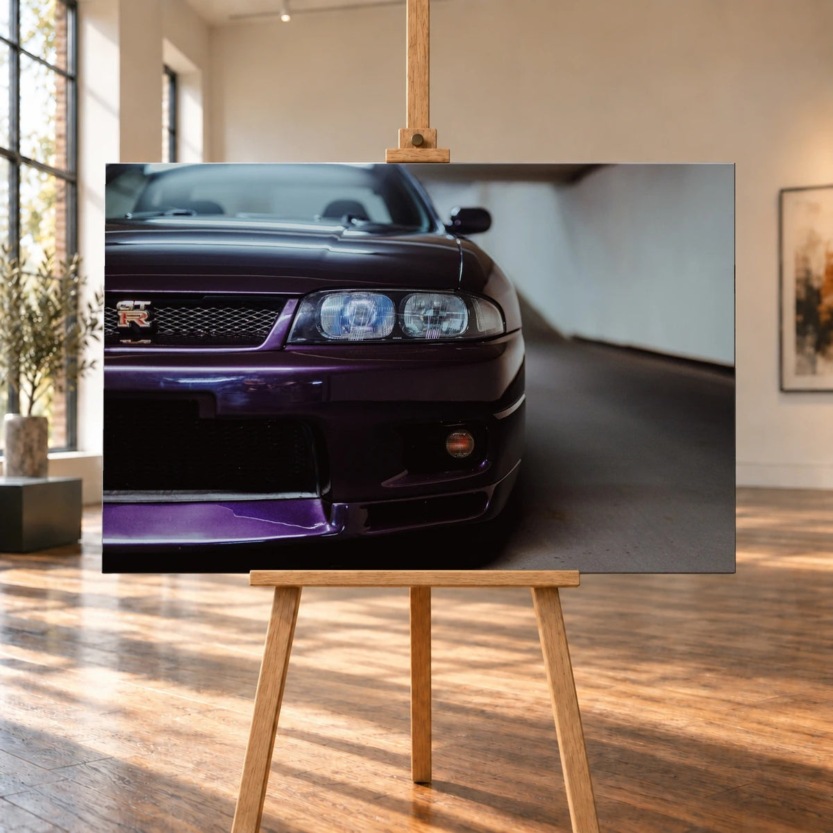 Raumvisualisierung mit einem Leinwandbild im Querformat auf einer Holzstaffelei. Große Fenster beleuchten den Holzboden; das frontal gezeigte Bild trägt die Nahaufnahme der violetten Front eines Nissan Skyline GT-R R33.