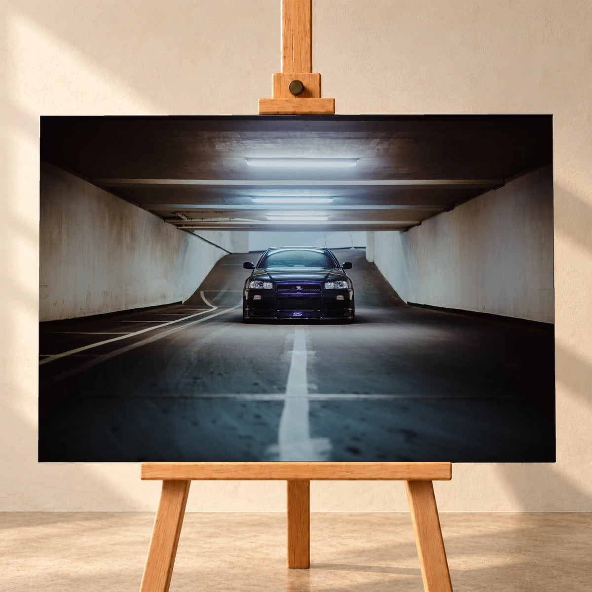 Visualisierung eines querformatigen Leinwandbilds auf einer Holzstaffelei vor heller Wand. Das Motiv zeigt einen dunkelvioletten Nissan Skyline GT-R R34 von vorn in einer Tiefgarage unter Leuchtstoffröhren.