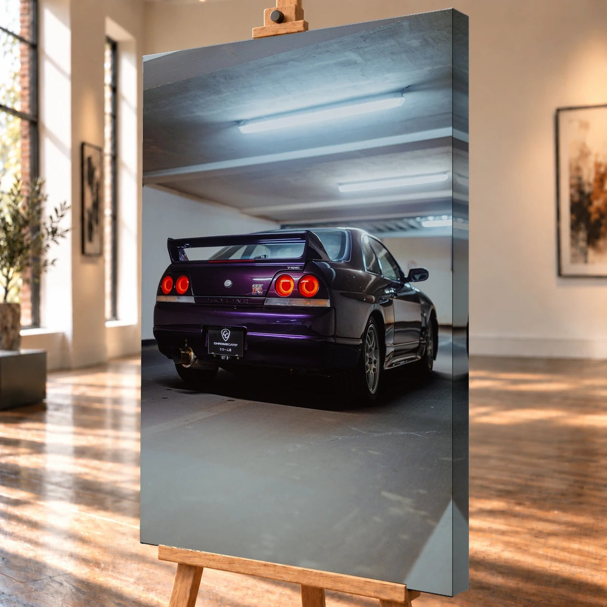 Schrägansicht eines Leinwandbilds als Visualisierung auf einer Holzstaffelei, mit sichtbarer bedruckter rechter Seitenkante. Im Garagenmotiv ist ein dunkelvioletter Nissan Skyline GT-R R33 V-Spec von schräg hinten mit Heckflügel und vier roten Rundrückleuchten zu sehen.