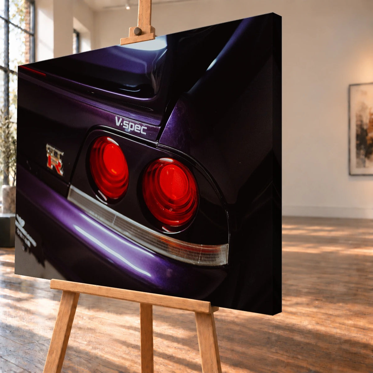 Schrägansicht einer visualisierten Leinwand auf einer Holzstaffelei, mit deutlich sichtbarer dunkler Seitenkante rechts. Auf dem Bild sind die roten runden Rückleuchten am violetten Heck eines Nissan Skyline GT-R R33 und der Schriftzug „V.spec“ zu sehen.