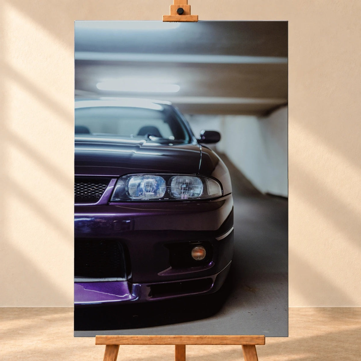 Visualisierung eines hochformatigen Leinwandbildes auf einer Holzstaffelei vor heller Wand. Das Motiv zeigt die violette Front eines Nissan Skyline R33 V-Spec mit Scheinwerferpartie und tiefem Stoßfänger in einer Garage.