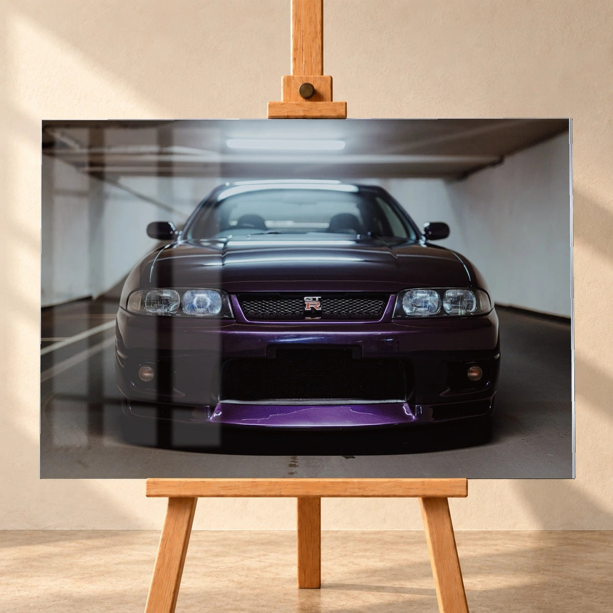Frontal visualisiertes Acrylglasbild auf einer Holzstaffelei vor heller Wand, mit Fensterspiegelungen über der linken Bildhälfte. Das querformatige Motiv zeigt einen dunkelvioletten Nissan Skyline GT-R R33 von vorn in einer Tiefgarage.