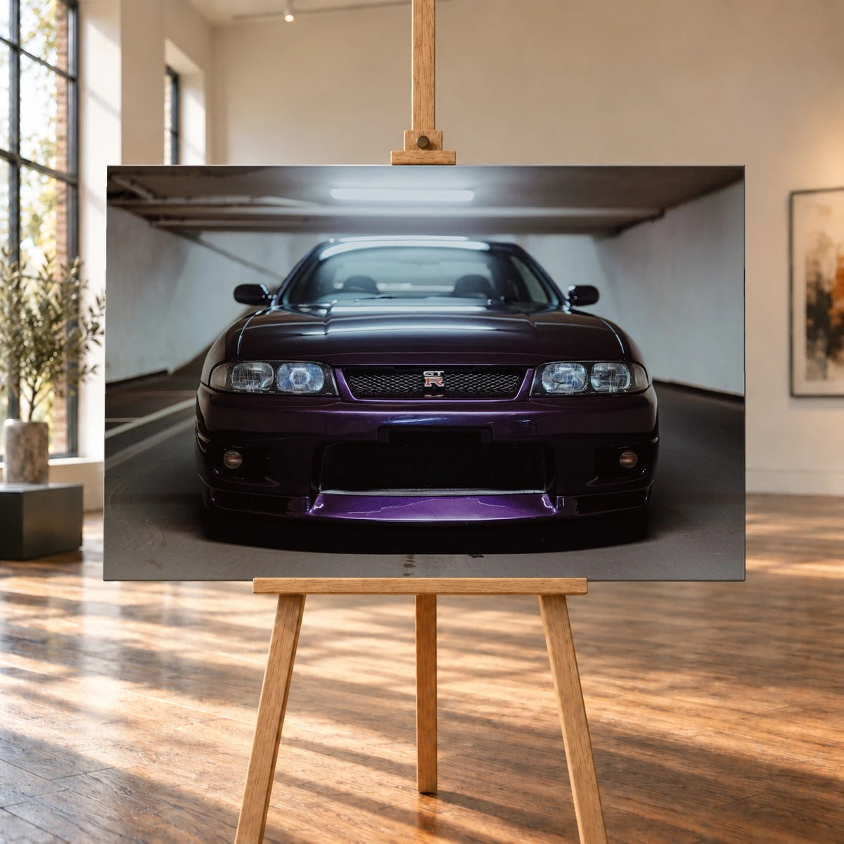 Raumvisualisierung eines querformatigen Leinwandbilds auf einer Holzstaffelei zwischen hohen Fenstern und sonnenbeschienenem Holzboden. Das Motiv zeigt einen dunkelvioletten Nissan Skyline GT-R R33 in Frontansicht in einer Tiefgarage.