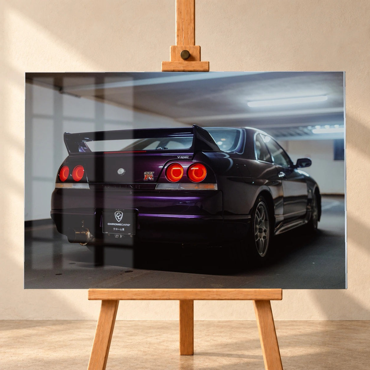 Als Acrylglas-Wandbild visualisiertes Garagenmotiv, frontal auf einer Holzstaffelei vor heller Wand. Ein dunkelvioletter Nissan Skyline GT-R R33 V-Spec ist schräg von hinten mit großem Heckflügel und roten Rundrückleuchten zu sehen. Fensterspiegelungen überlagern die linke Bildhälfte.