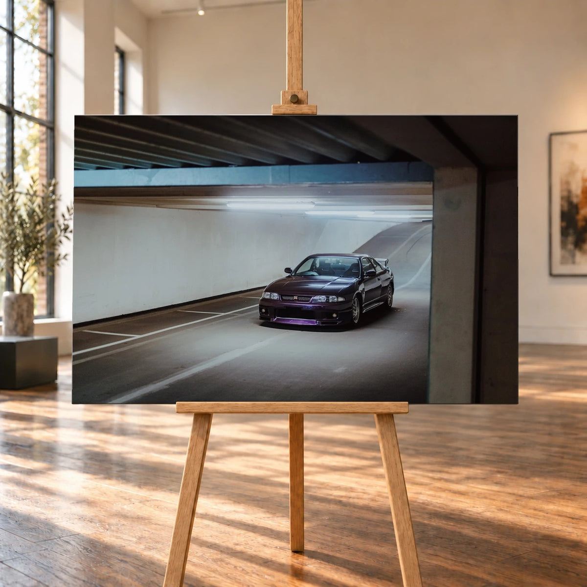 Raumvisualisierung mit einem Leinwandbild im Querformat auf einer Holzstaffelei in einem hellen Raum mit hohen Fenstern und Holzboden. Das Bild zeigt einen violetten Nissan Skyline GT-R R33 in einer Tiefgarage.