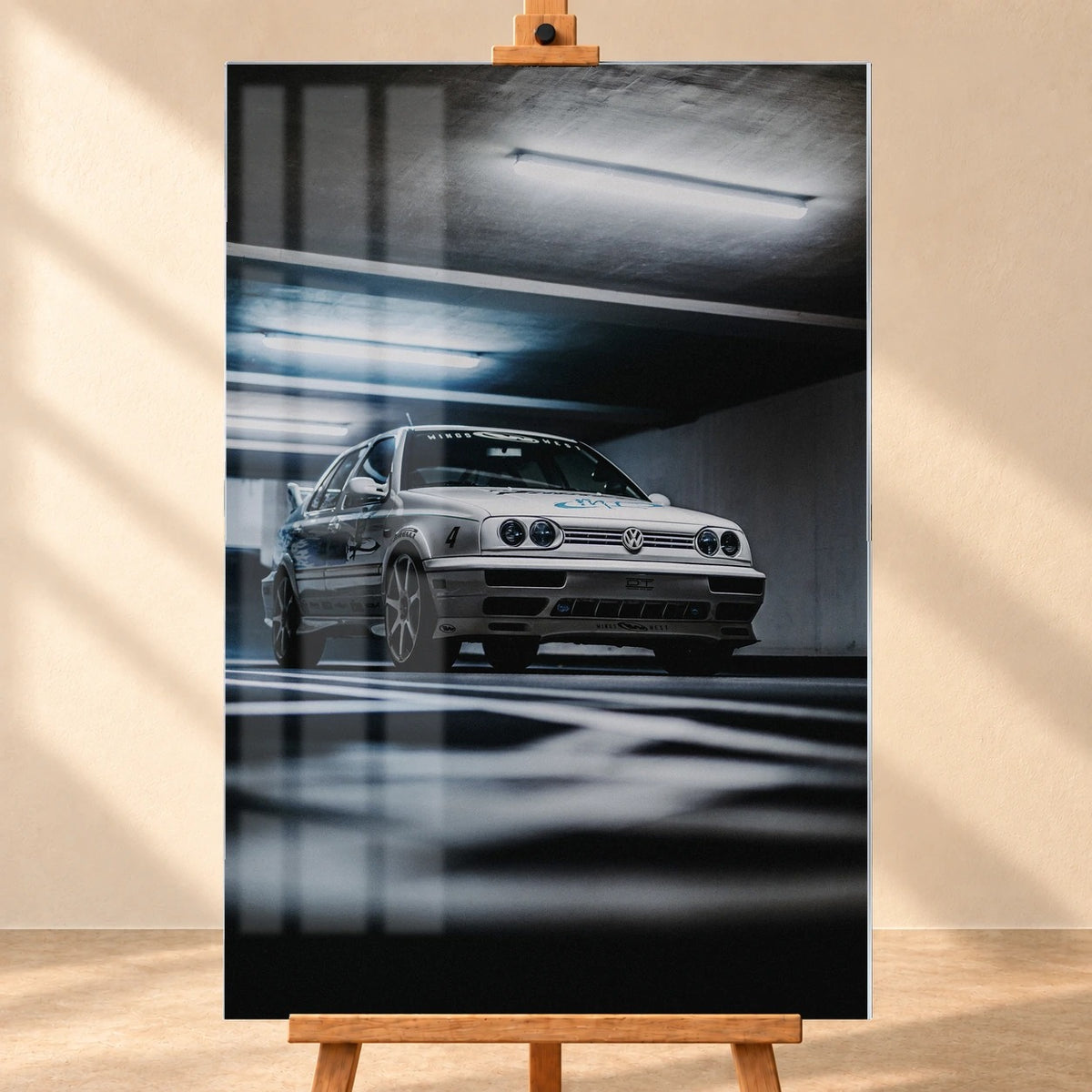 Jesses weißer VW Jetta aus „The Fast and the Furious“ in einer dunklen Garage, visualisiert als hochformatiges Acrylglasbild auf einer Holzstaffelei. In der frontalen Ansicht sind Fensterreflexionen über der linken Bildhälfte zu sehen.