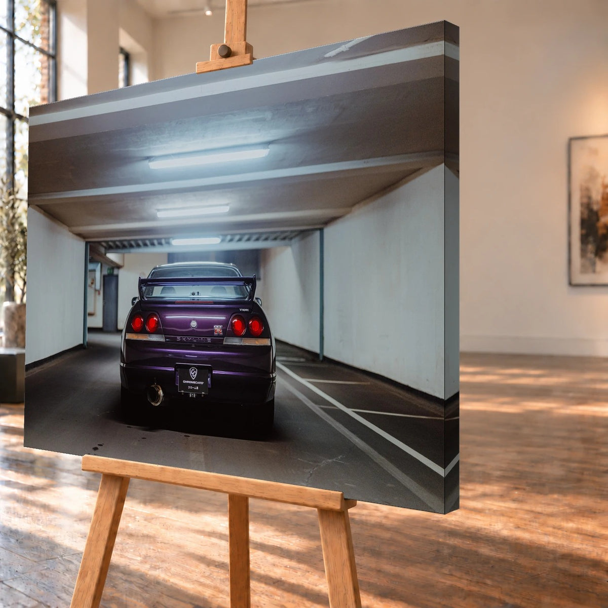 Schrägansicht eines Leinwandbilds als Visualisierung auf einer Holzstaffelei; die bedruckte rechte Seitenkante ist sichtbar. Auf dem Bild steht ein violetter Nissan Skyline GT-R R33 V-Spec mit markantem Heckflügel rückwärts zum Betrachter in einer beleuchteten Garage.
