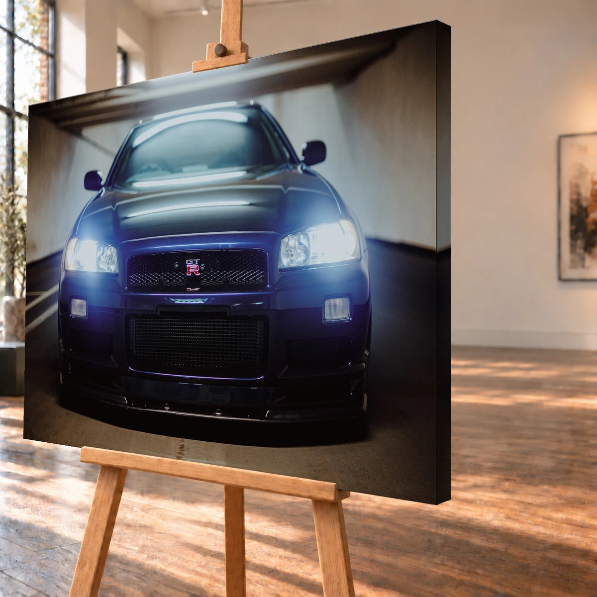 Schrägansicht eines Leinwandbilds als Visualisierung auf einer Holzstaffelei, mit deutlich sichtbarer rechter Seitenkante. Abgebildet ist die Front eines dunkelblau-violetten Nissan Skyline GT-R R34 mit eingeschalteten Scheinwerfern.