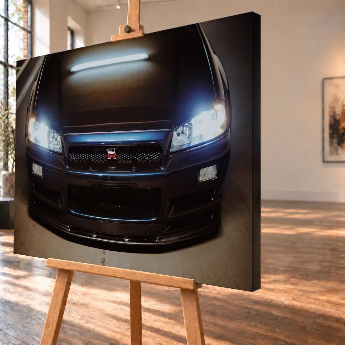 Schrägansicht eines Leinwandbildes als Visualisierung auf einer Holzstaffelei, mit deutlich sichtbarer rechter Seitenkante. Auf dem Bild ist die dunkelblaue Front des Nissan Skyline GT-R R34 mit leuchtenden Scheinwerfern und einem länglichen Lichtreflex auf der Motorhaube zu sehen.