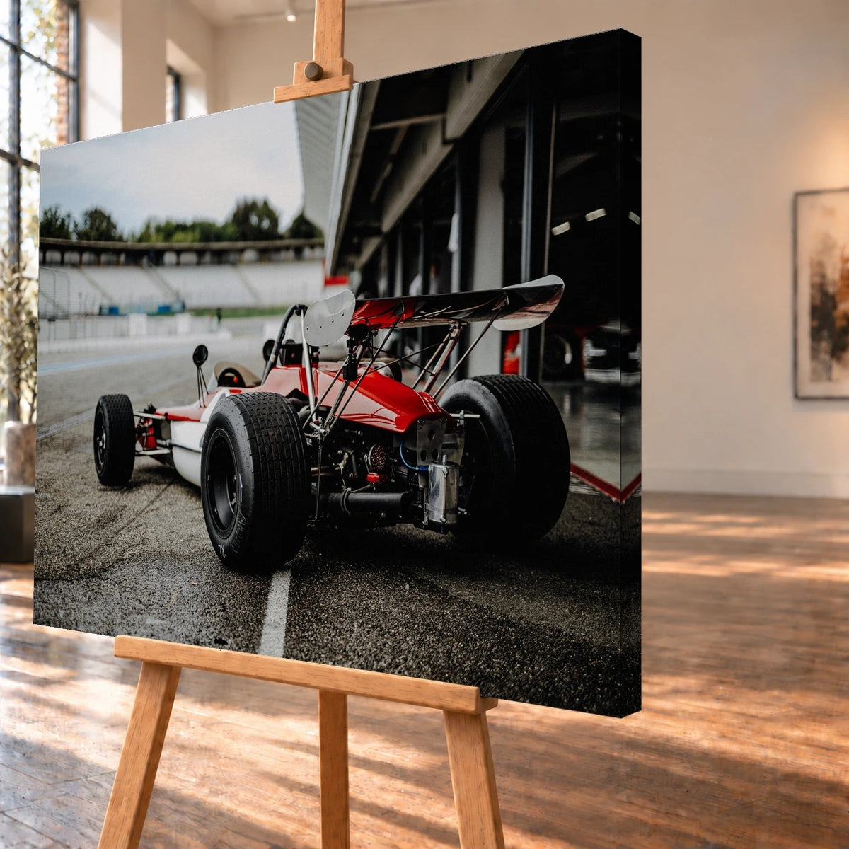 Schrägansicht eines Leinwandbilds als Visualisierung auf einer Holzstaffelei, mit deutlich sichtbarer bedruckter rechter Seitenkante. Abgebildet ist der rot-weiße Lotus 69 Formel 2 von schräg hinten vor den Boxen.