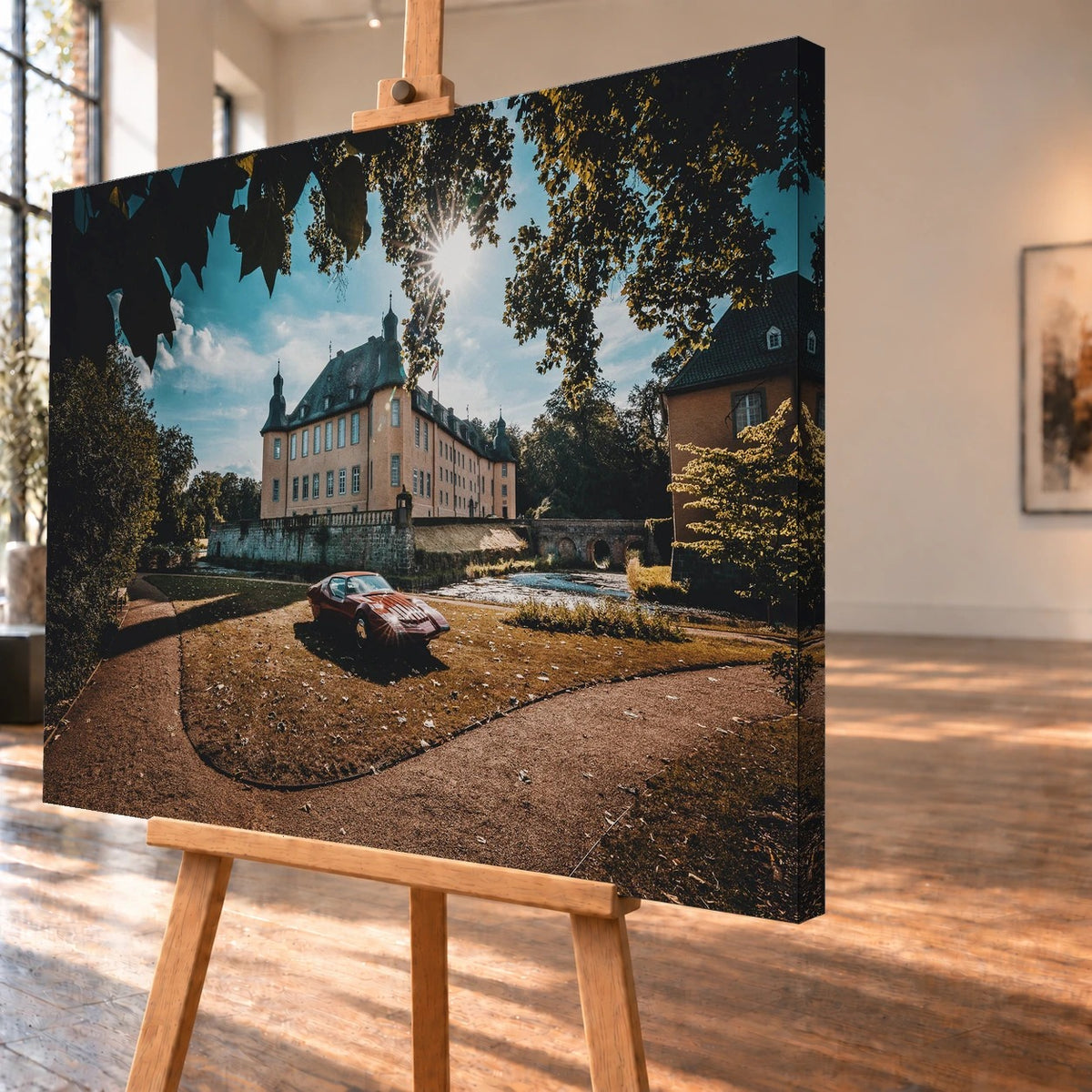 Schrägansicht eines Leinwandbilds als Visualisierung auf einer Holzstaffelei, mit sichtbarer rechter Seitenkante. Der rote Pontiac Number One steht im Motiv vor einem Schloss mit Wassergraben und Steinbrücke.