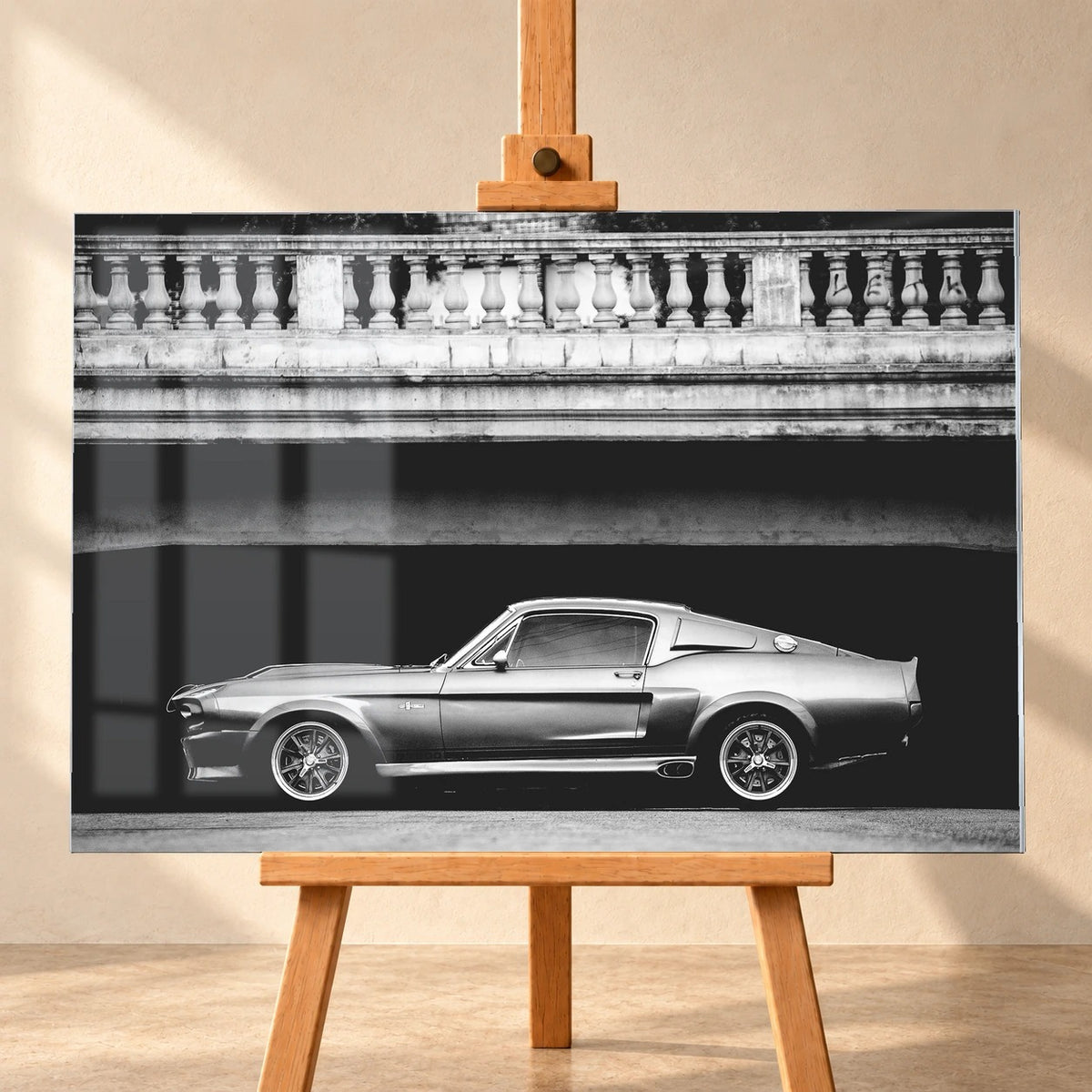 Visualisierung eines Acrylglas-Wandbilds in Frontalansicht auf einer Holzstaffelei. Fensterreflexionen überlagern links das Schwarz-Weiß-Motiv von Eleanor, dem Ford Mustang Shelby GT500 unter einer Brücke mit steinerner Balustrade.