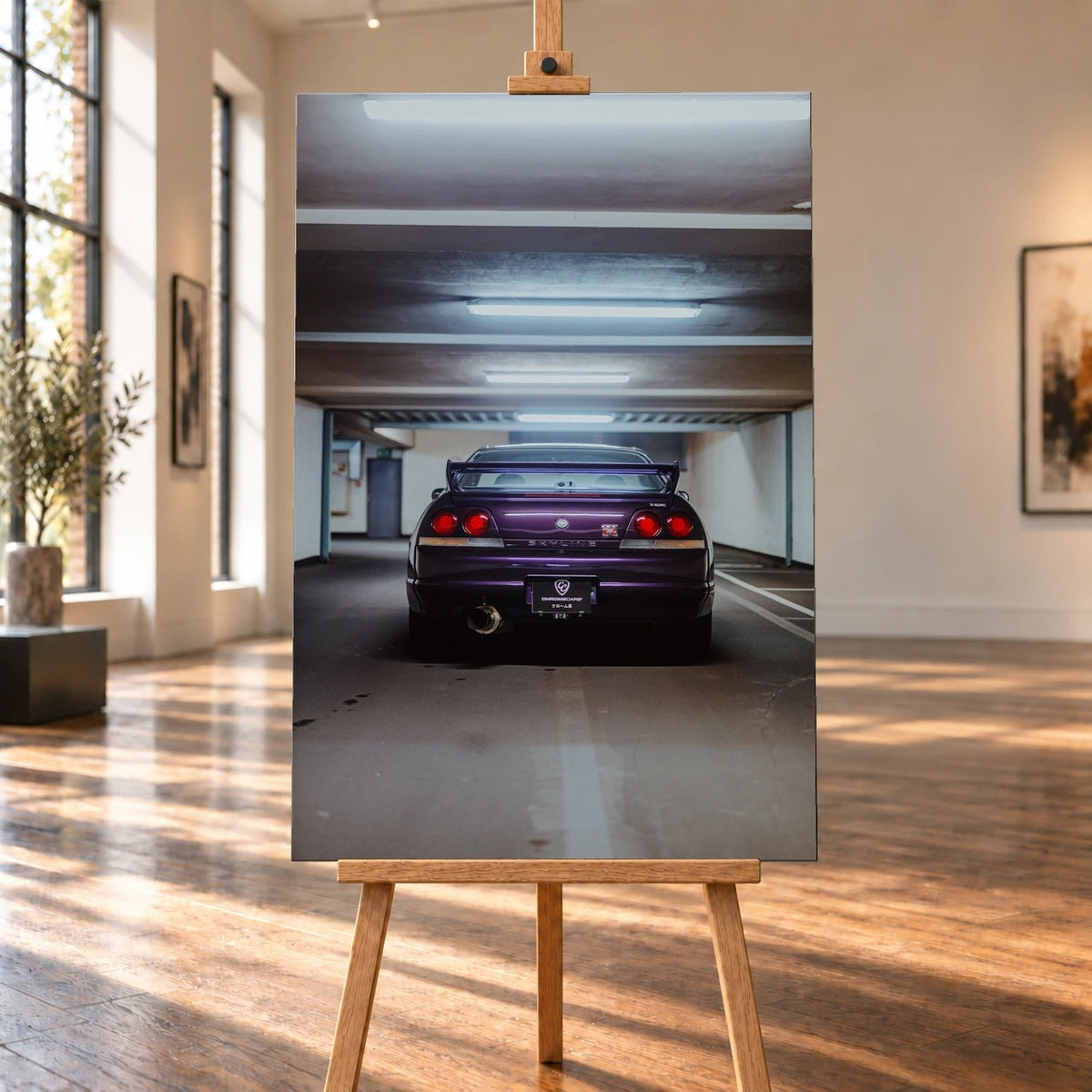 Raumvisualisierung eines hochformatigen Leinwandbilds auf einer Holzstaffelei in einem hellen Raum mit großen Fenstern und Holzboden. Auf dem Bild steht ein violetter Nissan Skyline GT-R R33 V-Spec mit dem Heck zur Kamera in einer Tiefgarage.