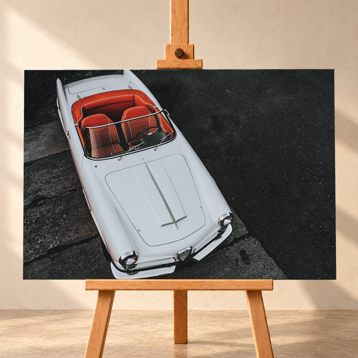 Heller Alfa Romeo 2000 Touring Spider in steiler Aufsicht, diagonal auf dunklem Asphalt; sichtbar sind das offene rot-orange Cockpit, Lenkrad, Windschutzscheibe, lange Motorhaube, runde Frontleuchten und Chromdetails; Visualisierung als Leinwand-Wandbild, frontal auf einer Holzstaffelei.