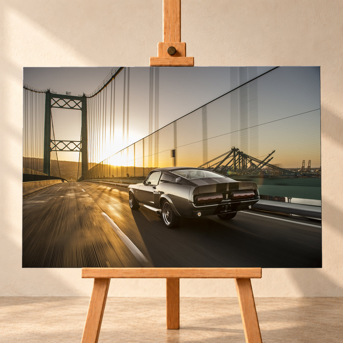 Dunkelgrauer Ford Mustang Fastback in Heck-Dreiviertelansicht auf einer Hängebrücke; goldenes Gegenlicht spiegelt sich auf der Fahrbahn, rechts sind Wasser und Hafenkräne zu sehen; Visualisierung als Leinwand-Wandbild, frontal auf einer Holzstaffelei.