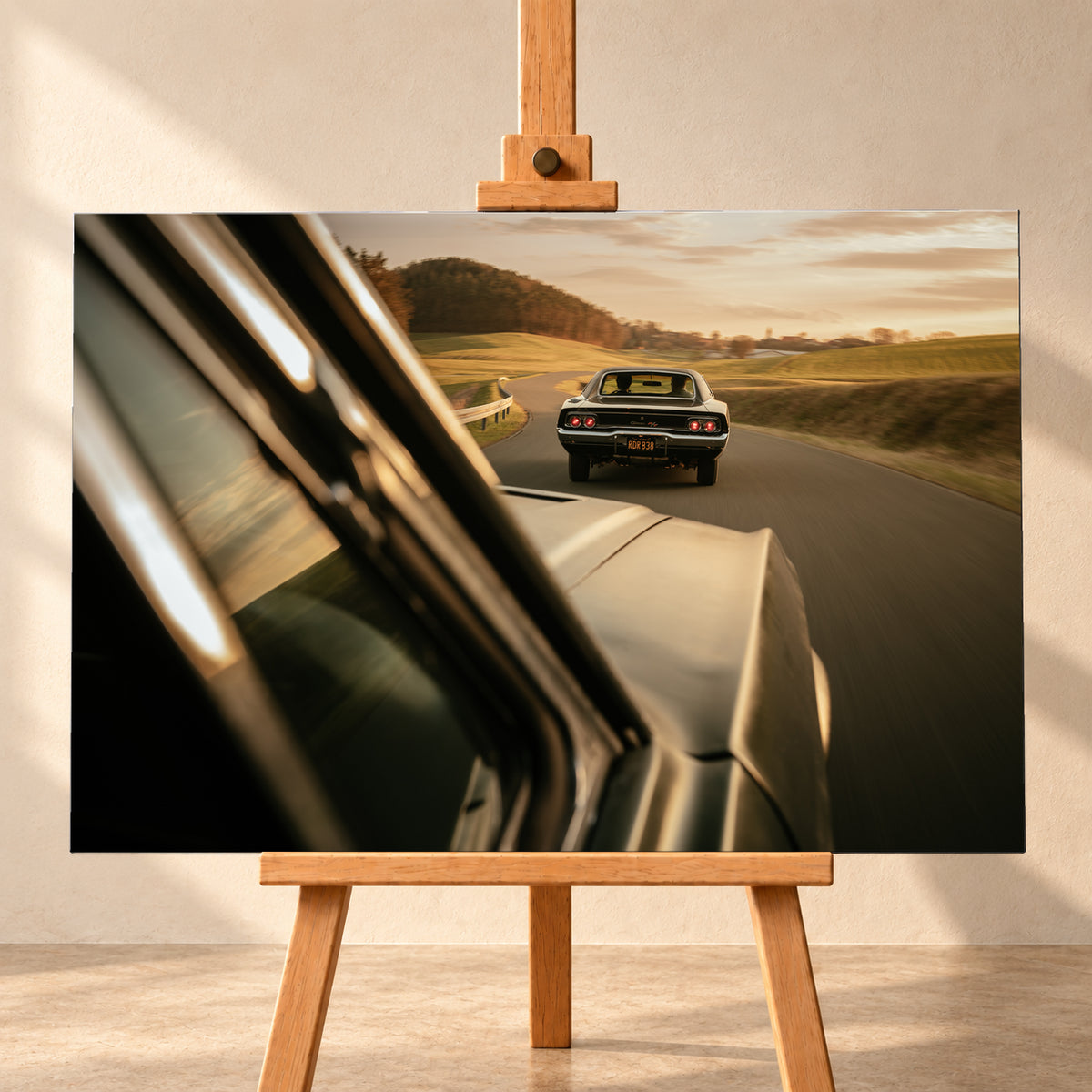 Dunkler Dodge Charger 440 R/T von hinten auf einer kurvigen Landstraße im goldenen Abendlicht, fotografiert aus einem zweiten fahrenden Auto; rote Rückleuchten, Wiesen und Bewegungsunschärfe; Visualisierung als Leinwand-Wandbild, frontal auf einer Holzstaffelei.