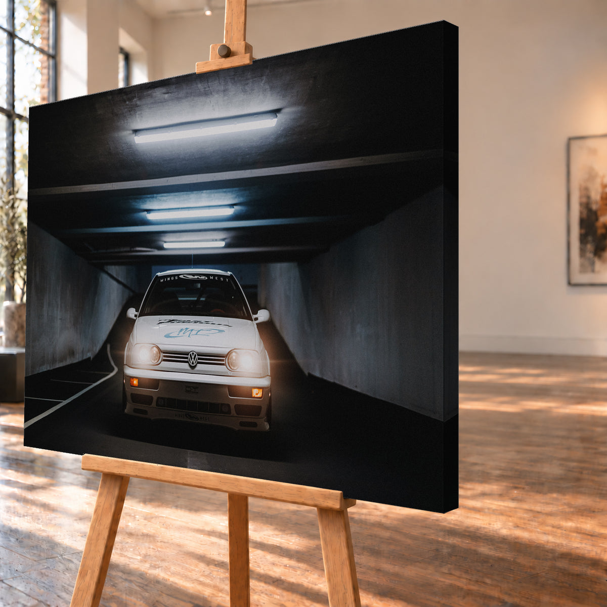 Weißer Volkswagen Jetta in frontaler Ansicht in einer dunklen Betongarage; Scheinwerfer und orangefarbene untere Leuchten sind eingeschaltet, darüber verlaufen helle Deckenröhren; Visualisierung als Leinwand-Wandbild, schräg von der Seite auf einer Holzstaffelei.