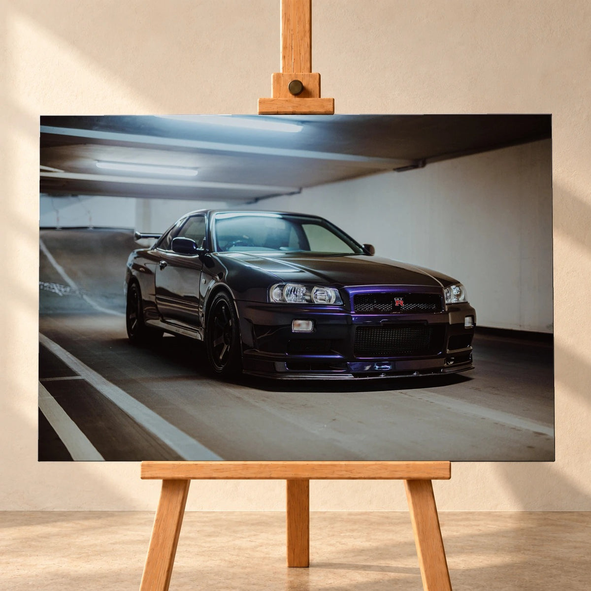 Visualisierung eines querformatigen Leinwandbildes auf einer Holzstaffelei vor heller Wand. Das Motiv zeigt einen dunkelvioletten Nissan Skyline GT-R R34 schräg von vorn in einer Tiefgarage.