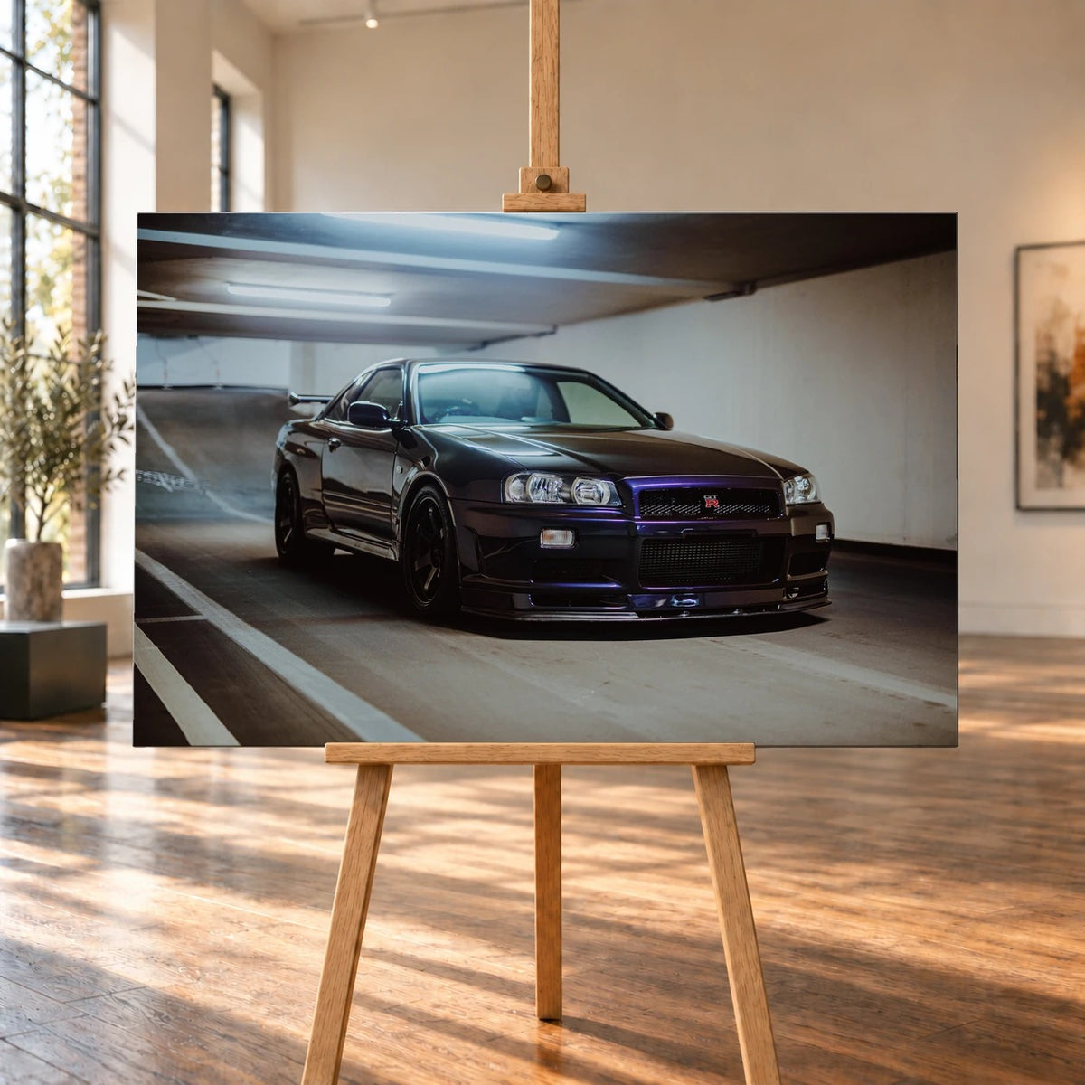 Raumvisualisierung mit einem querformatigen Leinwandbild auf einer Holzstaffelei in einem hellen Raum mit großen Fenstern und Holzboden. Im Bild steht ein dunkelvioletter Nissan Skyline GT-R R34 schräg zur Kamera in einer Tiefgarage.