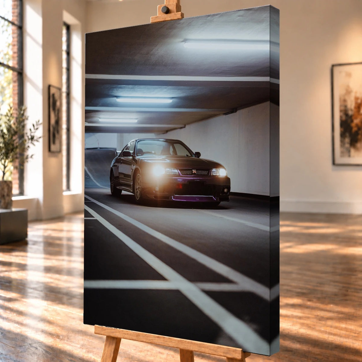 Schrägansicht eines Leinwandbildes als Visualisierung auf einer Holzstaffelei, mit sichtbarer bedruckter rechter Seitenkante. Auf dem Motiv steht ein dunkelvioletter Nissan Skyline GT-R R33 mit leuchtenden Scheinwerfern zwischen weißen Fahrbahnmarkierungen in einer Tiefgarage.