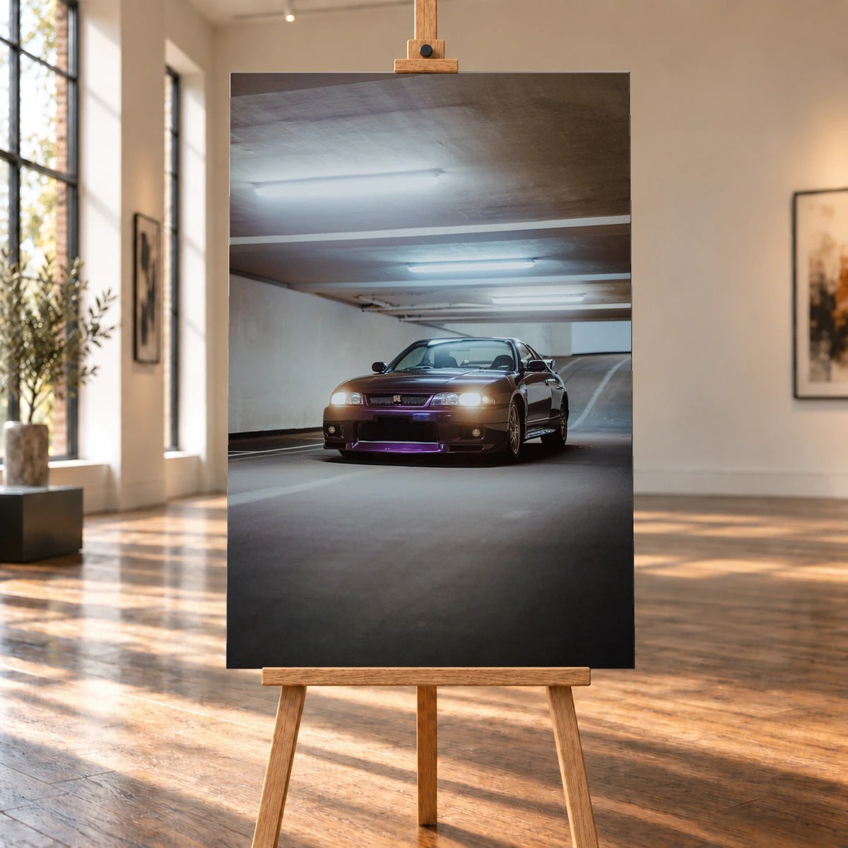 Raumvisualisierung einer hochformatigen Leinwand auf einer Holzstaffelei in einem hellen Galerieraum mit großen Fenstern und Holzboden. Das Bild zeigt einen dunkelvioletten Nissan Skyline GT-R R33 mit eingeschalteten Scheinwerfern in einer Tiefgarage.
