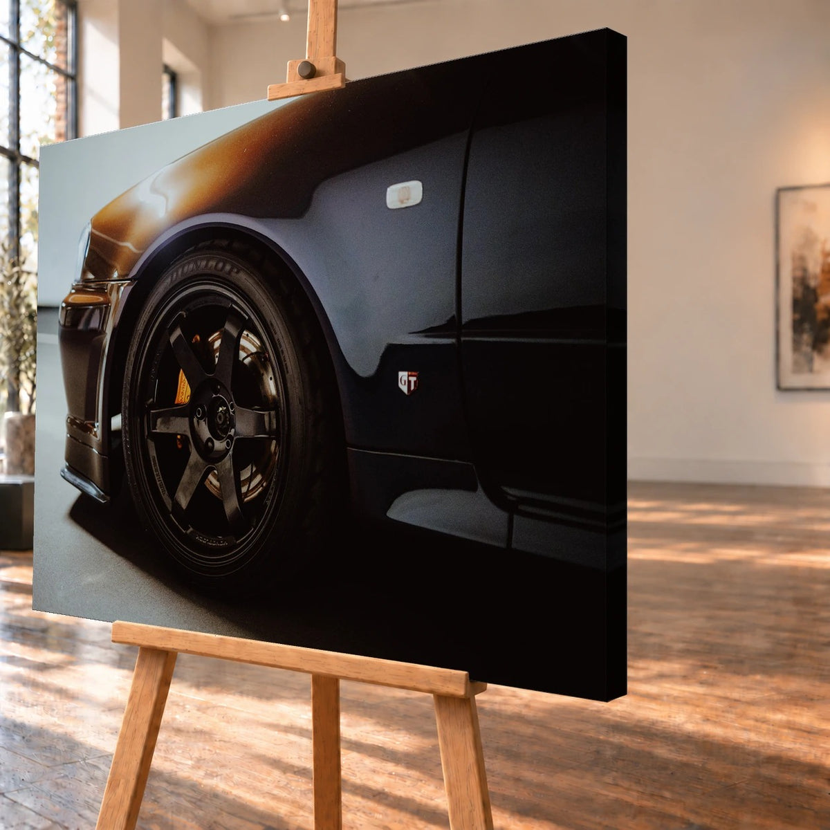 Schrägansicht eines Leinwandbilds auf einer Staffelei als Visualisierung, mit deutlich sichtbarer dunkler Seitenkante rechts. Auf dem Bild sind die vordere Radpartie und der Kotflügel eines dunklen Nissan Skyline R34 zu sehen.