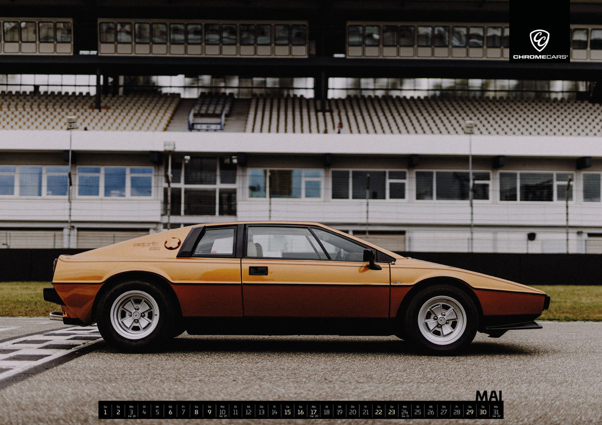 Black & Gold Collection Kalender 2027 – Mai: Der goldene Lotus Esprit steht streng im Seitenprofil vor der Boxenanlage; Keilform und dunkle Räder zeichnen eine klare Silhouette