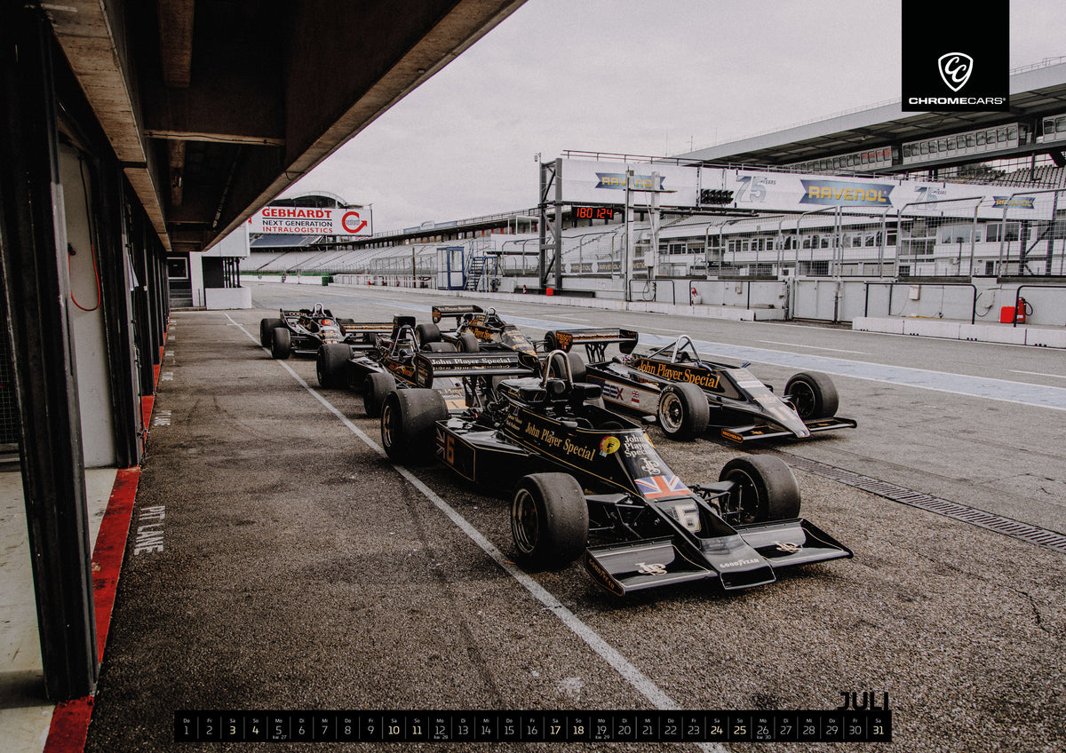 Black & Gold Collection Kalender 2027 – Juli: Mehrere historische Lotus-Rennwagen rollen in enger Formation an der Boxengasse entlang; der Blick von oben zeigt die Staffelung