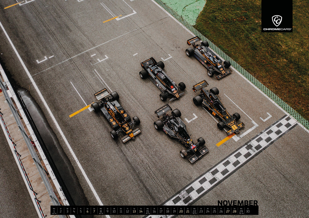 Black & Gold Collection Kalender 2027 – November: Fünf Lotus-Formelwagen stehen aus der Vogelperspektive nebeneinander auf der Startlinie; Markierungen und Asphalt erzeugen ein grafisches Raster