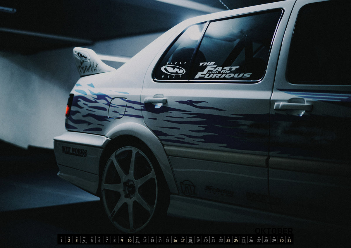 Jesse’s Jetta Kalender 2027 – Oktober: Nahaufnahme der hinteren Seitenpartie eines hellen VW Jetta mit blau-violetter Flammengrafik, großem Rad und Heckflügel. Im dunklen Seitenfenster steht „The Fast and the Furious“…