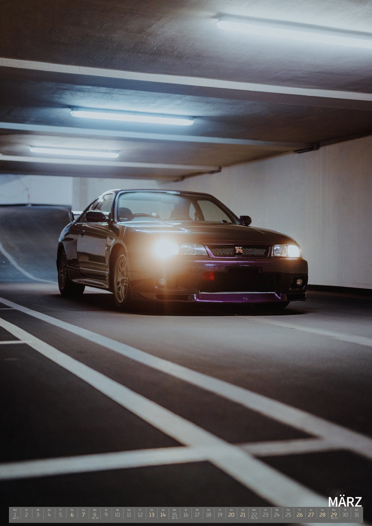 Midnight Purple I Kalender 2027 – März: Ein einzelner heller Scheinwerfer und der Nissan Skyline R33 am Ende der Spur prägen die vertikale, stark in die Tiefe gezogene Komposition