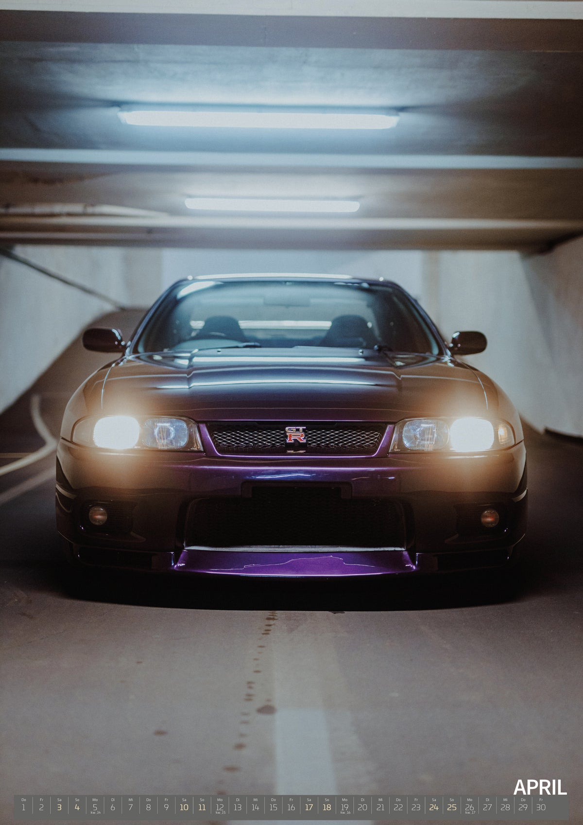 Midnight Purple I Kalender 2027 – April: Die Front des Nissan Skyline R33 erscheint im Hochformat mit eingeschalteten Scheinwerfern; violetter Splitter und kaltes Neonlicht kontrastieren miteinander