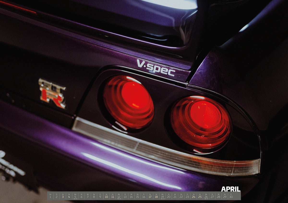 Midnight Purple I Kalender 2027 – April: Eine enge Heckaufnahme zeigt zwei rote Rundlichter, GT-R- und V-Spec-Schriftzug sowie den violetten Lack des Nissan Skyline R33