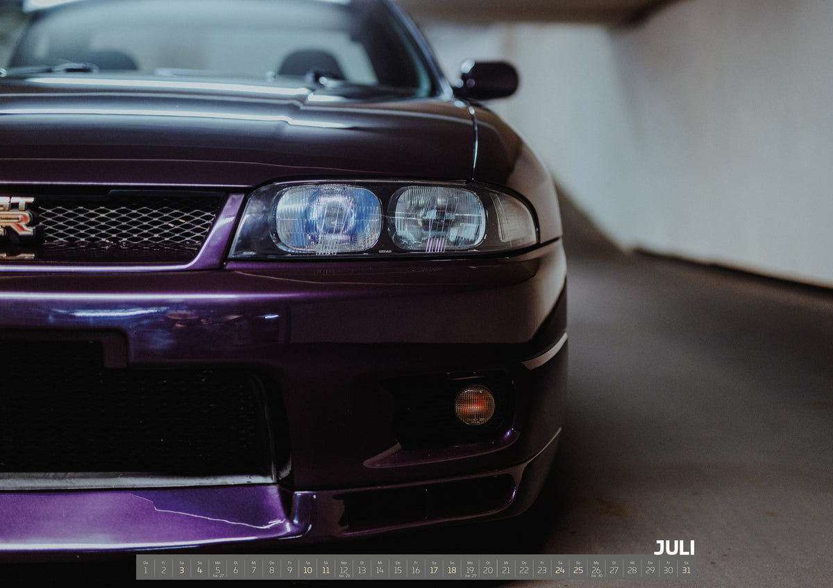 Midnight Purple I Kalender 2027 – Juli: Die angeschnittene Front des Nissan Skyline R33 zeigt auf engem Raum Grill, Scheinwerfer und violetten Splitter als grafisches Detail