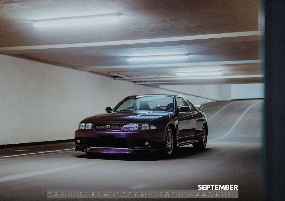 Midnight Purple I Kalender 2027 – September: Eine dunkle Betonstütze rahmt den Nissan Skyline R33 in der Parkhauskurve; das Fahrzeug wird seitlich aus dem Schatten heraus sichtbar