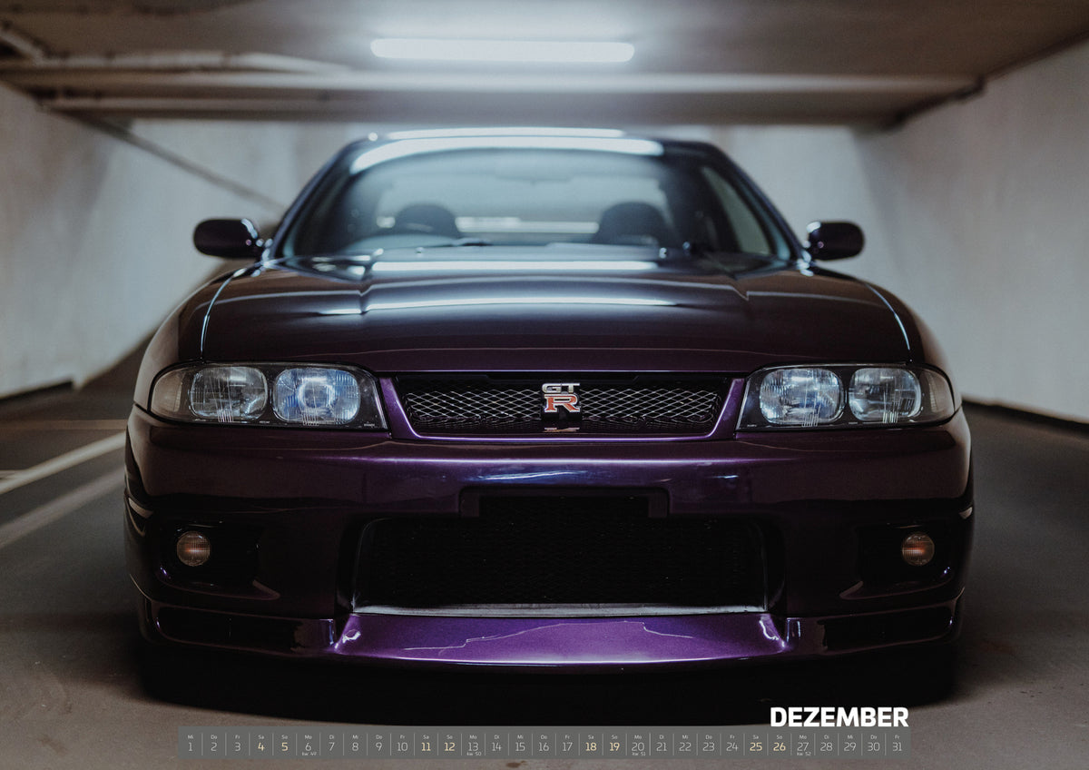 Midnight Purple I Kalender 2027 – Dezember: Der Nissan Skyline R33 ist frontal und nah unter Neonlicht fotografiert; Kühlergrill und violetter Splitter bilden eine klare horizontale Linie