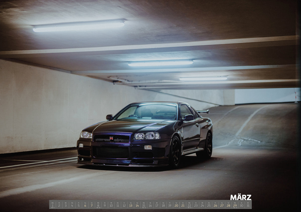 R34 Midnight Purple II Kalender 2027 – März: Der Nissan Skyline R34 nähert sich optisch aus einer breiten, geschwungenen Parkhausspur; das violette Auto steht im Zentrum des Lichtkegels