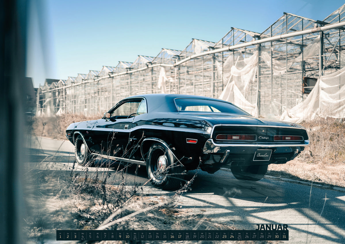 ChromeCars Retrospektiv II Kalender 2027 – Januar: Der schwarze Dodge Challenger ist schräg von hinten auf einem Industriegelände aufgenommen; breite Karosserie und rote Rückleuchten wirken kraftvoll