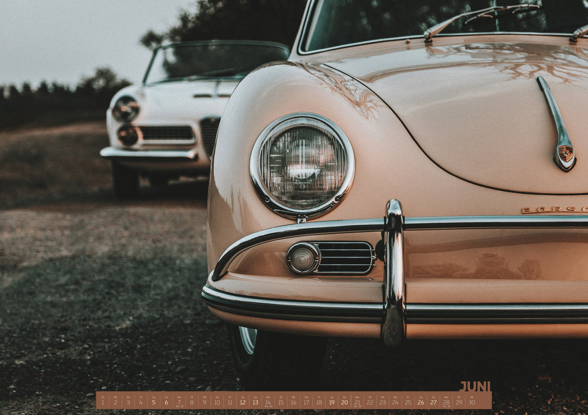 ChromeCars Retrospektiv Kalender 2027 – Juni: Nahaufnahme der Front eines roséfarbenen Porsche 356 A mit Rundscheinwerfer und Chromstoßfänger rechts; links dahinter steht unscharf ein heller Alfa Romeo 2000 Touring Spider auf…
