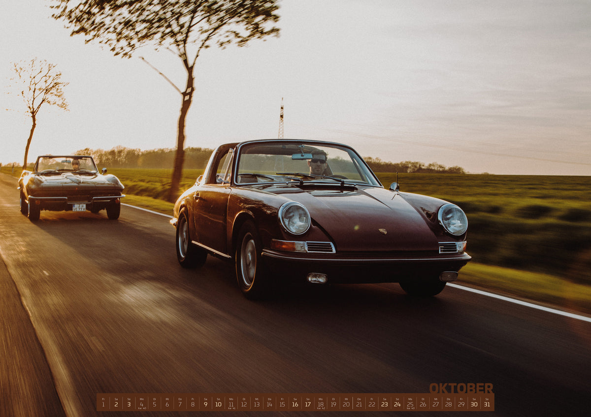 ChromeCars Retrospektiv Kalender 2027 – Oktober: Ein dunkelrot wirkender Porsche 911 S Softwindow fährt rechts im Vordergrund, dahinter links eine dunkle Chevrolet Corvette C2; beide mit offenem Dach und sichtbaren Fahrern auf einer…