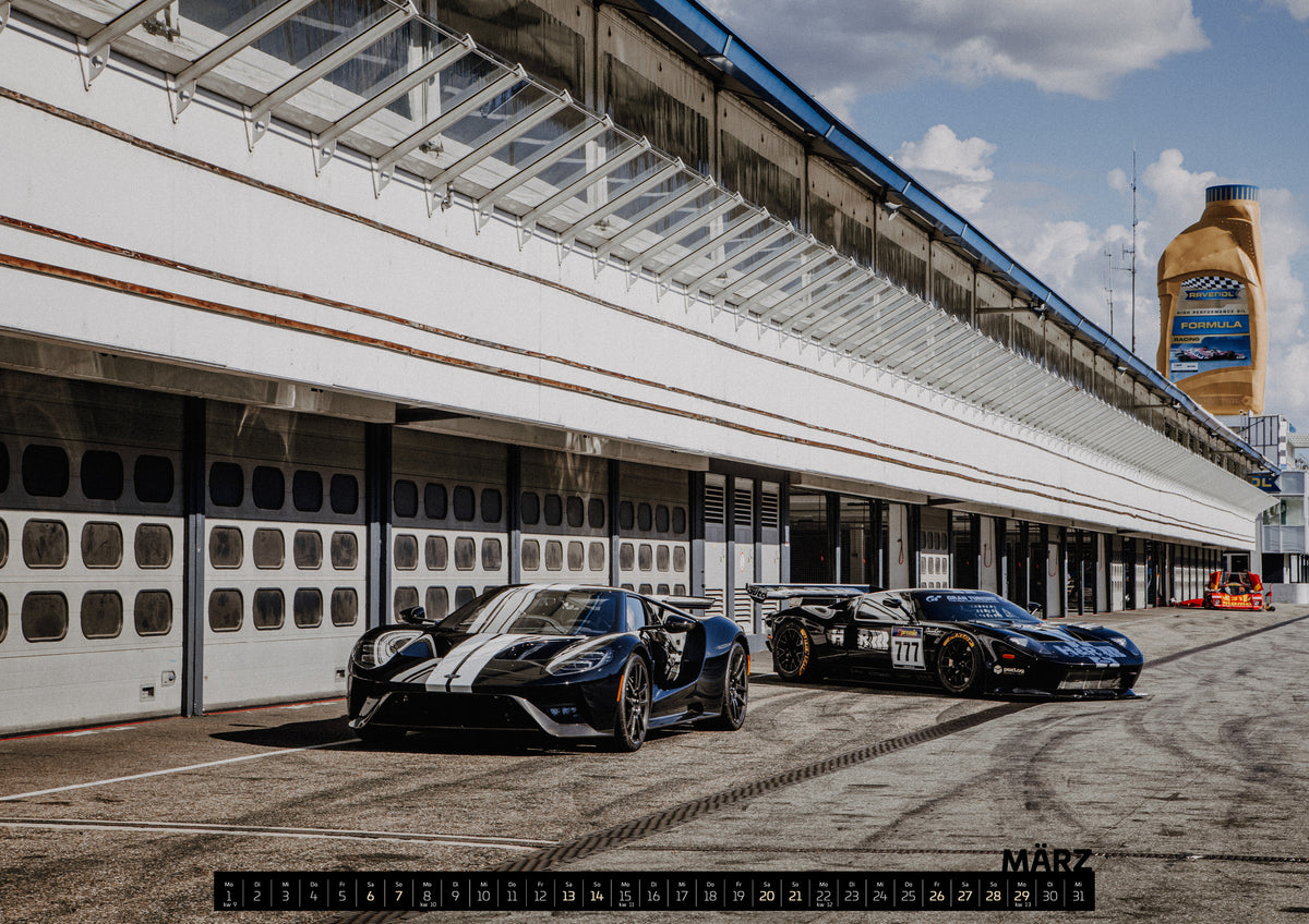 Trackday Kalender 2027 – März: Der Ford GT GT3 steht flach und dunkel in der hellen Boxengasse; lange Gebäudelinien und blauer Himmel führen in die Tiefe