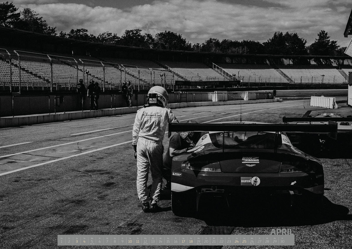 Trackday Kalender 2027 – April: Der Aston Martin Vantage V12 GT3 Billy steht von hinten in der Boxengasse; eine Person lehnt am geöffneten Heckbereich und gibt dem Bild Maßstab